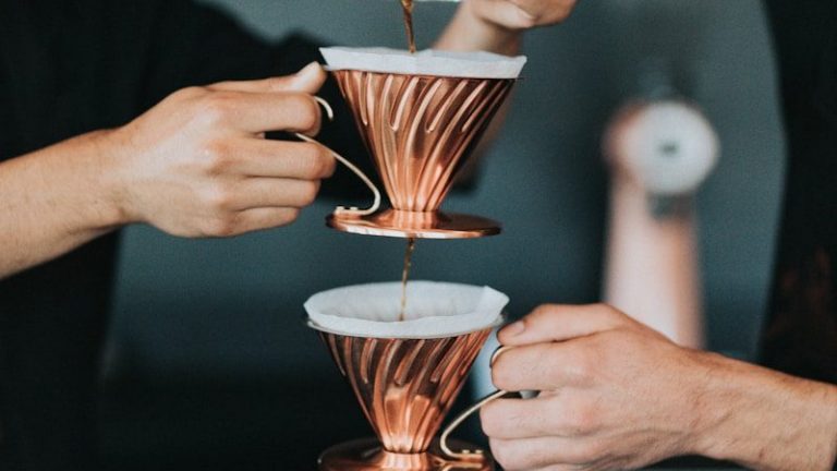 two person pouring coffee with piled cups